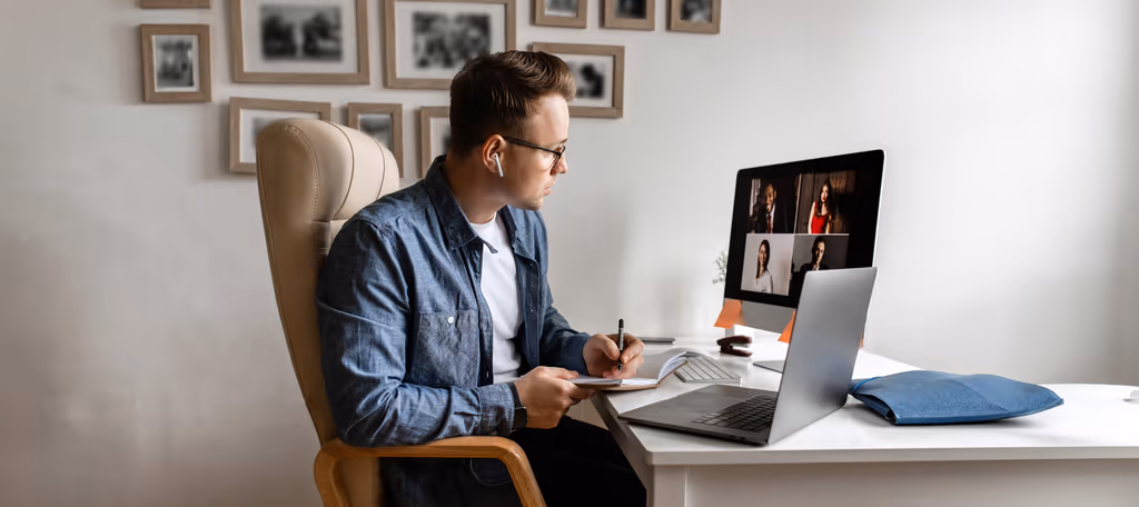 A person working from home at a desk with a laptop and an external monitor